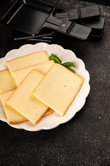 Raclette cheese portion slicing natural product tasty snack fresh delicious gourmet food background on the table rustic top view copy space