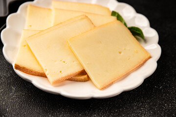 Raclette cheese portion slicing natural product tasty snack fresh delicious gourmet food background on the table rustic top view copy space