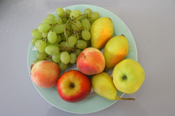 Grapes, apples and peaches on a blue plate.