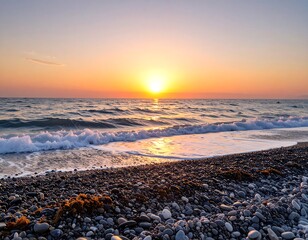 Obraz premium A vibrant sunrise paints the coastal scene with warm hues, showcasing waves gently lapping at a pebble beach.