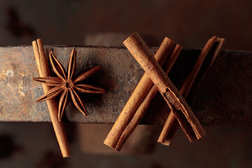 Cinnamon sticks and anise on a rusty background.