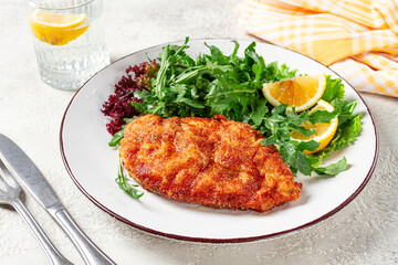 Milanese chicken, Crispy breaded chicken served, with fresh herbs, and lemon wedges,
