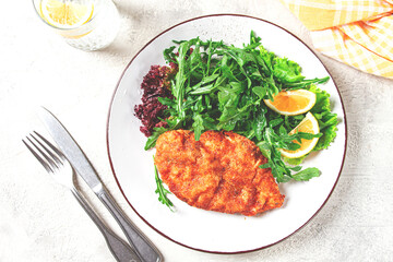 Milanese chicken, Crispy breaded chicken served, with fresh herbs, and lemon wedges,