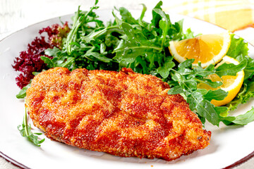 Milanese chicken, Crispy breaded chicken served, with fresh herbs, and lemon wedges,