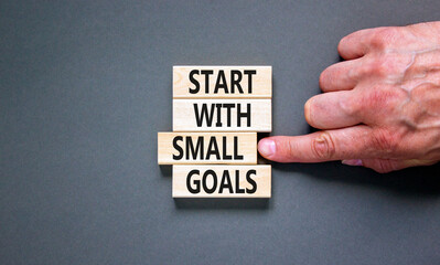Start with small goals symbol. Concept words phrase Start with small goals on beautiful wooden blocks. Beautiful grey background. Businessman's hand. Business Start with small goals concept Copy space