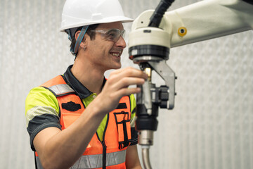 Engineer in safety gear smiling while operating industrial robot in modern factory, concept of automation, robotics, workplace safety, and positive engineering environment. AI learning