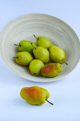 bamboo plate with ripe pears on light background, close-up	
