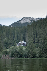 Secluded Forest House Beneath Rocky Mountain Ridge Reflected in Lake