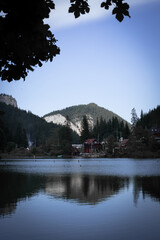 Still Reflection of a Mountain Village Beneath Green Hills and Pine Forests