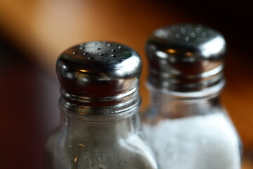 Two salt and pepper shakers on a wooden table, perfect for decorating your kitchen or as a prop in still life photography