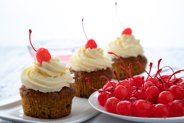 Homemade muffins with whipped cream and canned cherries on a bright morning table