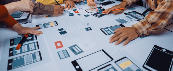 A vibrant design session showing diverse hands engaged in creating user interface prototypes. The table displays sketches, digital devices, and collaborative tools fostering creativity. SACTR