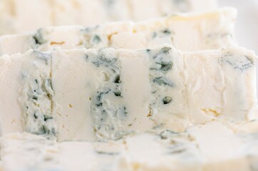 Slices of creamy, decadent blue cheese exhibit vibrant marbling. The texture looks rich and invites a gourmet experience. A must-have for cheese enthusiasts