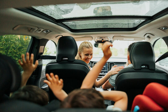 Happy woman enjoying with family sitting in car during weekend trip