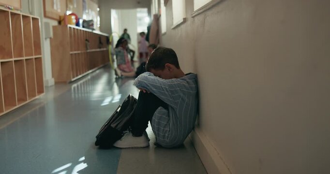 Depression, education and student boy in hallway of school for development or learning failure. Anxiety, lonely and sad with unhappy child in corridor of academy for mistake, regret or study trouble