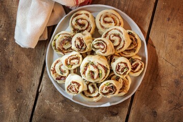 A top-down view of a white plate filled with rolled and cut pinwheels of dough, highlighting...