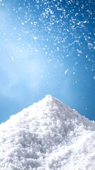 A large pile of fresh snow sits against a bright, clear, winter sky filled with falling snowflakes.