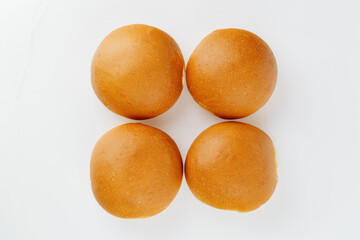 Top view of four fresh golden burger buns on white background, minimalistic bakery concept