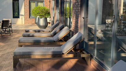 Sunlit lounge chairs rest serenely on the wooden deck, perfect for Whispering Wind Day relaxation or Nordic Midsummer retreat