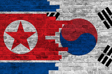 colourful painted big national flag of south korea and flag of north korea on a massive old brick wall background.