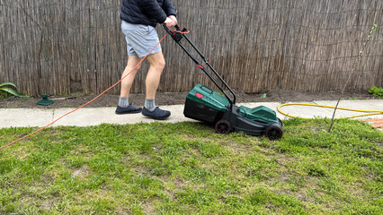 A Caucasian man tending sprawling backyard with electric mower, embodying Lawn Appreciation Day and...