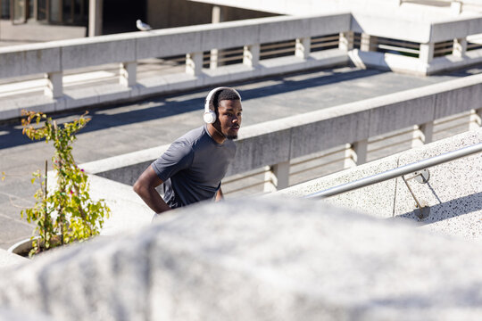 African american man running up concrete stairs at parking garage with white headphones