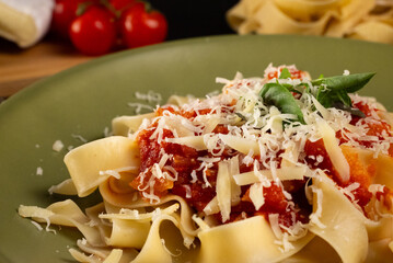 Extreme close-up of fresh pasta with tomato sauce. The detailed texture of grated parmesan cheese,...