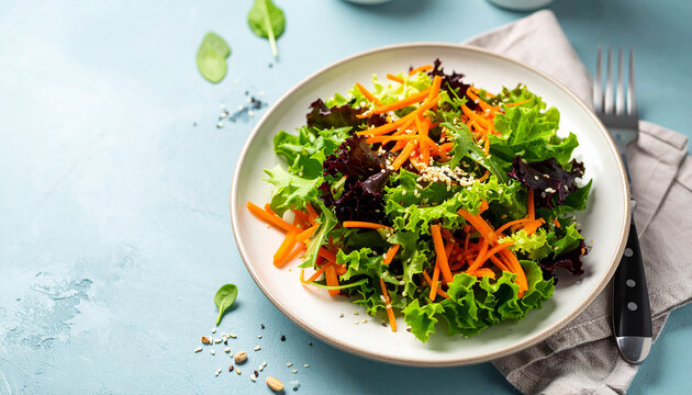 Colorful mixed salad with leafy greens, julienned carrots and sesame seed sprinkle. Natural food.
