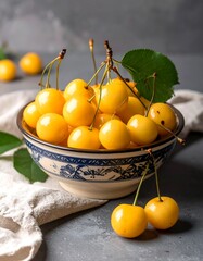 A vibrant bowl overflowing with plump, golden yellow cherries, displayed against a muted gray background.