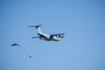 RAF Airbus C.1 A400M Atlas military transport aircraft in flight on a low-level cargo drop run, CDS parachute dropped, blue sky