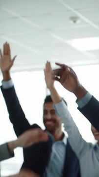 Medium close-up video capturing diverse professional hands rising in unison in a bright, modern corporate meeting room, signifying unanimous approval. Business consensus concept
