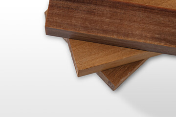 Three pieces of wood exhibiting distinct shades and grain patterns are stacked on a light background, ideal for crafting and design purposes in woodworking.