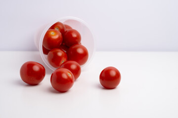 Cherry tomatoes in a plastic cup on a white background. Farm products close-up
