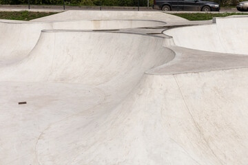 Curved concrete ramps are designed for skateboarders in this urban skatepark, offering a smooth surface for tricks. The park is located near greenery, creating a vibrant atmosphere