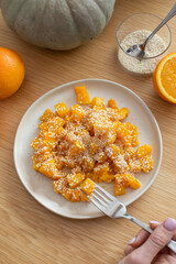 Healthy orange pumpkin salad with honey, orange and sesame seeds on wooden table with fresh citrus