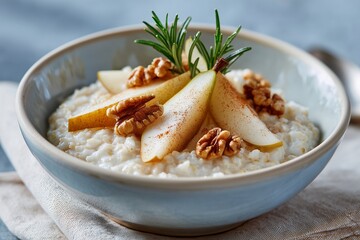 Bowl of creamy oatmeal topped with fresh pear slices, walnuts, and a sprig of rosemary, showcasing a delicious and healthy breakfast option for a nutritious start