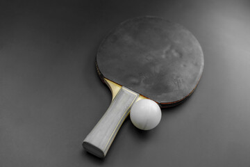 Table tennis paddle with ball positioned on a black background for sport and recreation enthusiasts