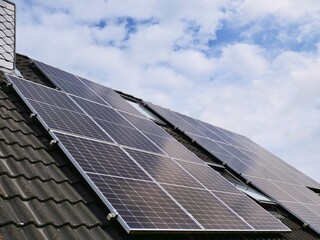 Fototapeta premium Photovoltaic panels providing green energy on rooftop under blue sky