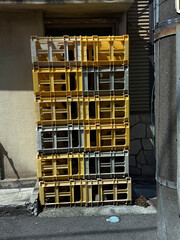 Plastic crates stacked against a wall. Urban life concept. Handheld mobile photo, selective focus, harsh sunlight, non AI