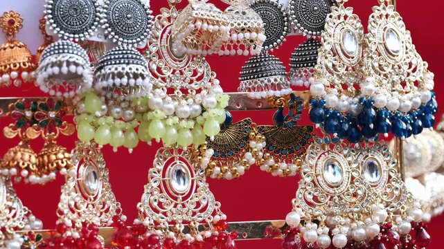 Colorful jhumka earrings with pearls and gemstones are hanging and showing indian craftsmanship
