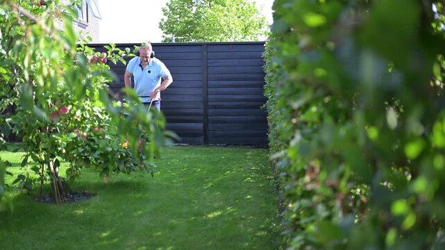 A middle-aged man mows the grass in his yard