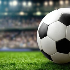 A soccer ball rests on a grassy field, set against a blurred stadium backdrop, creating a dynamic sports image.
