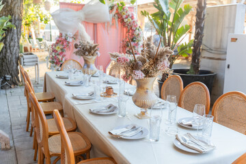 An elegantly set outdoor dining table adorned with lush floral centerpieces, ready for a wedding, party, or special celebration