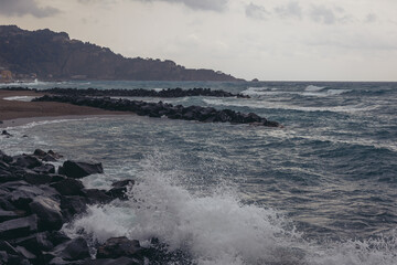 Ionian Sea coast in Giardini Naxos in the Metropolitan City of Messina on the island of Sicily, Italy. Taormina city on background