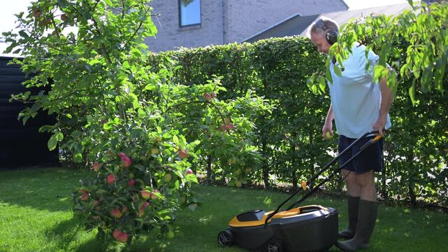 A middle-aged man mows the grass in his yard