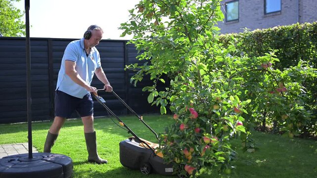 A man cuts the grass in his garden using a machine