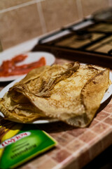 Cooking Golden Crepe Pancakes on Griddle in Rustic Kitchen with Fresh Tomatoes