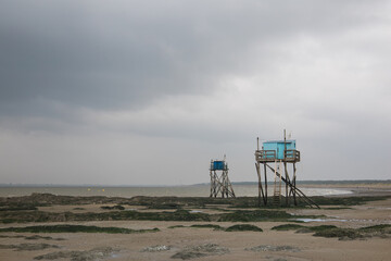 Naklejka premium pêcherie traditionnelle sur la plage des dunes à Saint-Michel-chef-chef sur le littoral de Loire Atlantique en France en été sous un ciel nuageux