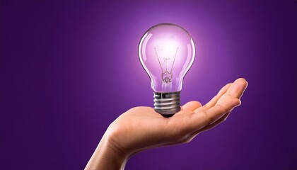 hand holding a glowing light bulb on purple background image photo