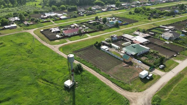 Green fields and houses characterize this rural landscape, showcasing a water tower amidst cultivated plots